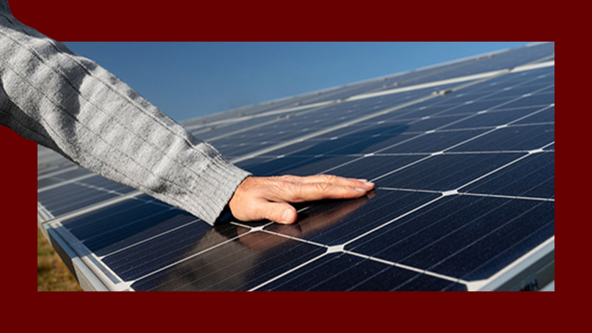Mão de um senhor sobre uma das placas de energia solar